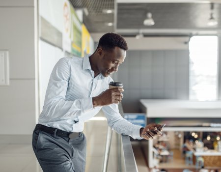 Young black businessman with cup of coffee, food-court. Successful business person in office cafe, black man in formal wear